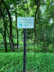 For your safety please walk with a friend sign on a nature path