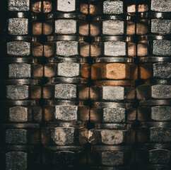 A striking arrangement of metallic pipe rings, layered in a grid pattern, with a central golden ring illuminated by light filtering through the textured surfaces.