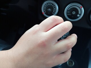 The driver's hand on the gear shift knob in the interior of a black car. The topic of driving a car with a manual transmission.