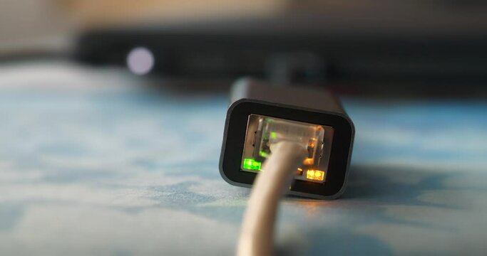 Internet cable through an adapter connected to the laptop. Working ethernet cable adapter with green LED and flashing yellow LED