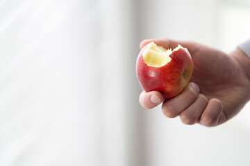 male hand holding bitten apple copy space, man eating an apple close up selective focus