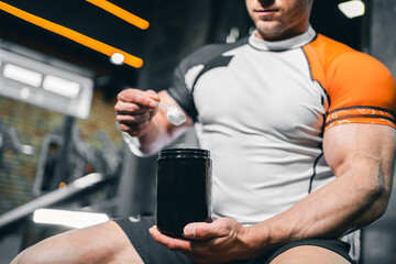 Fototapeta na wymiar muscular bodybuilding athlete with perfect body holding protein or whey jar mockup in gym, athletic man in fitness club preparing sport nutrition and supplement