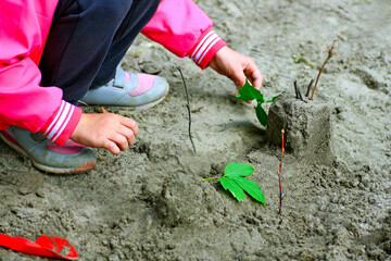 The child plays with sand and plants.