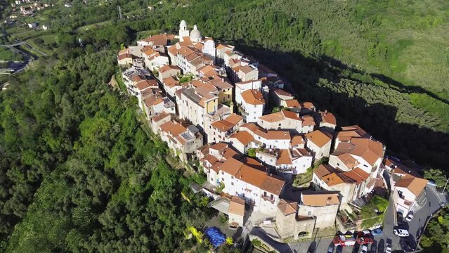  A charming hilltop village nestled in the greenery of Luni, near Sarzana, between Liguria and Tuscany, seen through the lush foliage at dusk. a drone video of the borgo