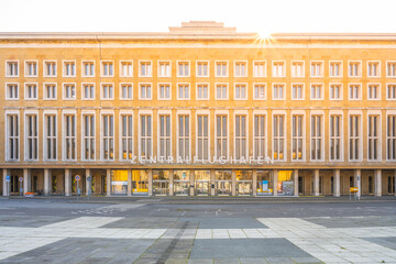 Sunlight flares above the historic Tempelhof Airport terminal in Berlin, casting a warm glow on its...