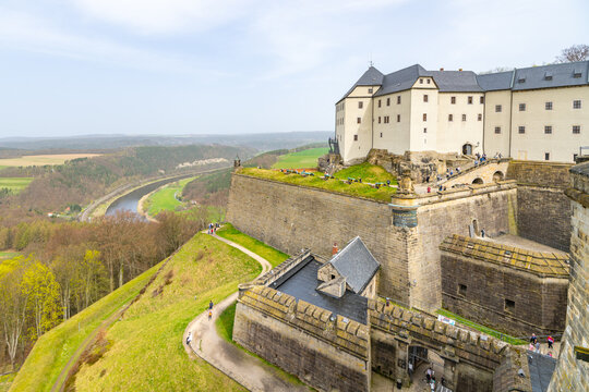 A view of the historic Konigstein Fortress in Saxony, with visitors on the ramparts and the Elbe River in the background. Garmany