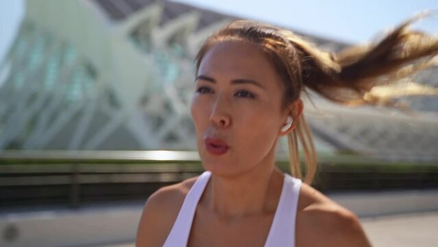 Asian oriental adult woman jogger in sportswear running workout lace up sunny morning urban high tech city background. Jogging training marathon, endurance result cardio exercise Healthy lifestyle
