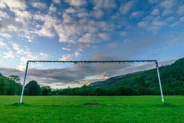 Wide-angle view from behind heavily used goalposts at a football pitch in the South Wales valleys...