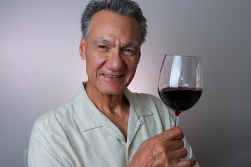 Mature Man smiling and holding up a big glass of red wine