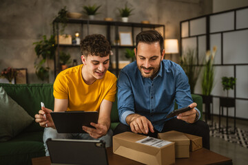 Two caucasian men colleagues scan package with mobile phone at home