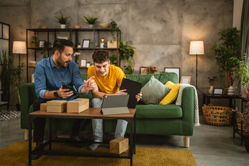 Two men check package delivery shipment status on tablet at home