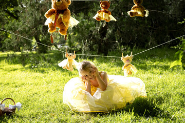 Smiling girl playing near teddy bears in sunlit garden.