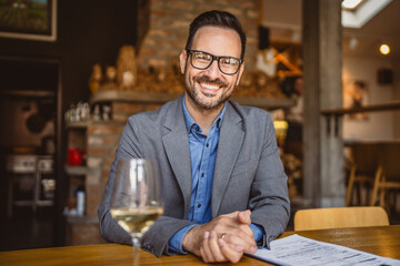 Adult man sit in a winery with glass of wine and clipboard