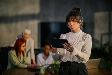 Young businesswoman in formal wear using tablet at corporate firm.