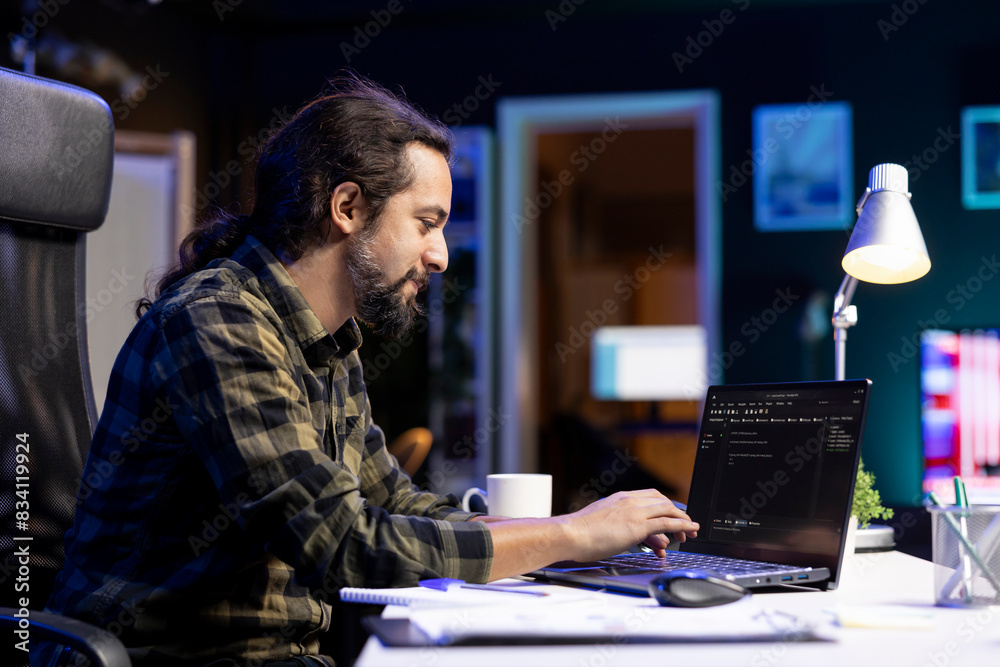 Poster male programmer works on his portable computer, managing the database and monitoring network for cyb