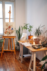 Creative art studio with easel and plants on table with no people.