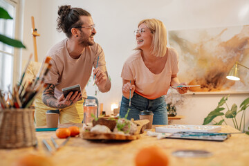 Artistic couple creating artwork at atelier and smiling at each other.