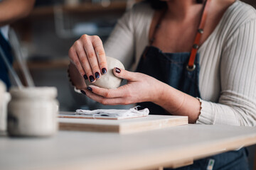 Close up of pottery class student's hands modeling clay at workshop.