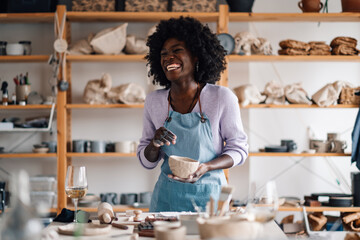 Happy diverse potter at ceramics studio with clay work in hands laugh