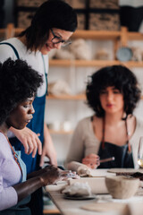 Diverse pottery course attendees learning pottery with tutor.