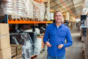 Portrait of positive man in blue shirt in a store warehouse