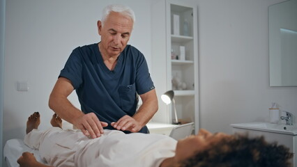 Practitioner touching woman stomach in hospital ward. Doctor massaging patient