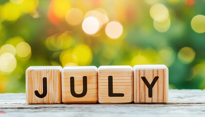 Wooden blocks with word JULY, natural green backdrop. Summer time concept. Close-up.