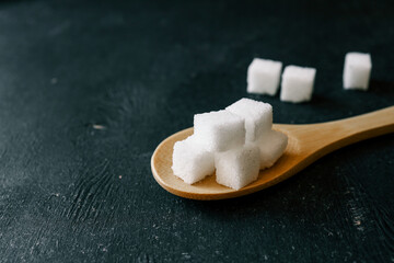 White crystalline sugar cubes on a wooden spoon