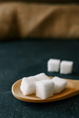 White crystalline sugar cubes on a wooden spoon
