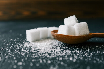 White crystalline sugar cubes on a wooden spoon