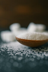 White crystalline sugar cubes on a wooden spoon