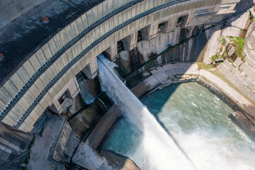 Dam water release, aerial view from drone. Water steam flows from power plant reservoir. Green and...