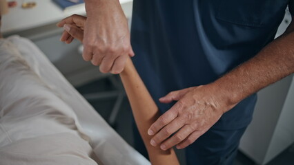 Closeup osteopath treating hand on therapy session. Physiotherapist examine arm