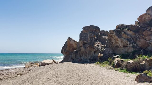 Wide-angle view of a scenic beach with a prominent rocky outcrop, blue sea, and clear sky. costa del sol, sotogrande, andalusia. playa de sardina
