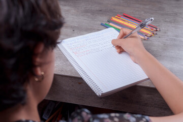 Hands of a young woman doing homework, she writes in her notebook, homework topic.