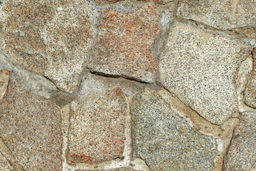 Fototapeta premium Closeup of brown stone wall made of natural rocks and cement as a background