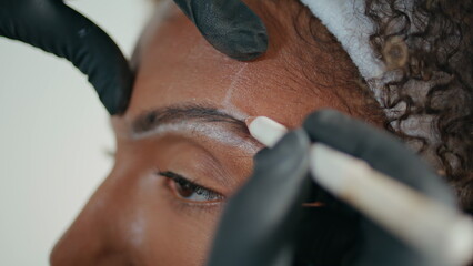 Closeup cosmetician marking brows with pencil. Hands in gloves shaping contour