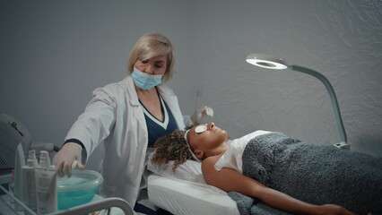 Beautician cleaning woman skin with cotton pads. Facial treatment in clinic.