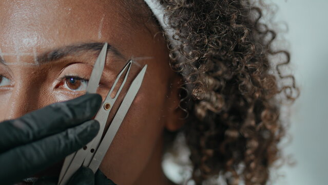 Closeup hands marking brows for permanent makeup. African american visit salon