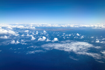 Aerial view of Hawaiian island of Molokai and its western coast against blue sky with clouds