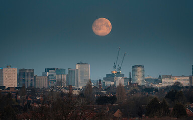 Moon setting over Birmingham city skyline at dawn