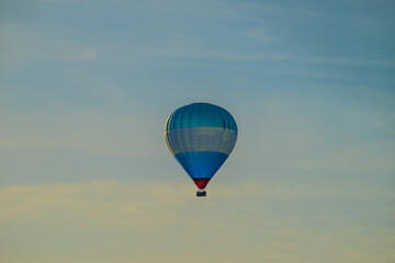 Blue white and red hot air balloon in evening sun.