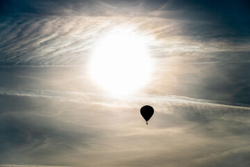 Hot air balloon rising towards the sun.