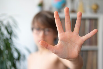 Child, 11-year-old boy extending hand to signal stop, stopping gesture, alert action, complains...