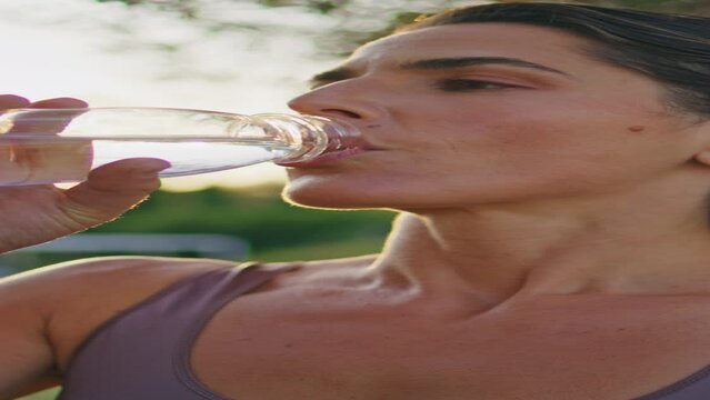 Athletic lady renewing water balance intense workout in sunrise vertical closeup