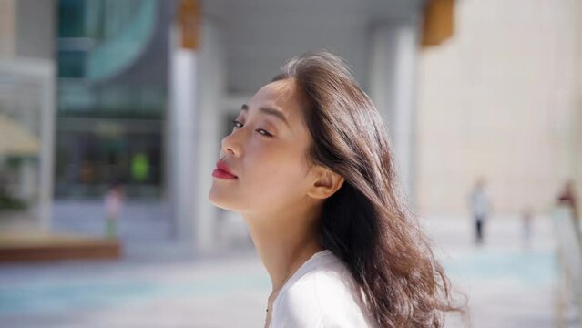 charming young lady looking at camera smile in the summer morning sunlight at urban city street
