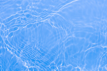 Blue water with ripples on the surface. Defocus blurred transparent blue colored clear calm water surface texture with splashes and bubbles. Water waves with shining pattern texture background.