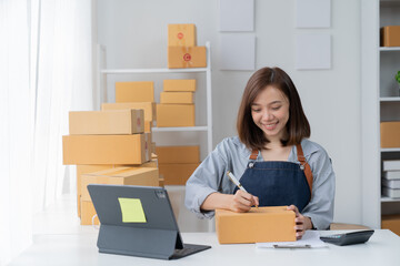 SME entrepreneur Small business entrepreneurs Online selling ideas, Happy  Asian business owner work on computer and a box at home, delivery SME procurement package box deliver to customers,