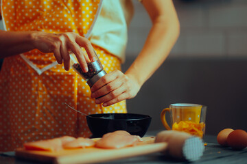 Woman Using ground pepper to season the meat. Cook seasoning her meal with a mix of black and red...