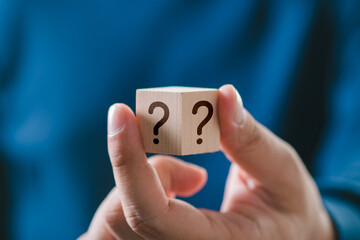 The concept of finding an answer to complex questions in business. Hand holding a wooden cube box...